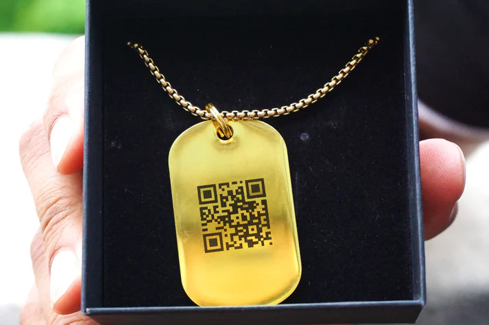 Close-up view of a golden Jump tag QR code necklace with Jumplink QR side up, presented in an open jewelry box